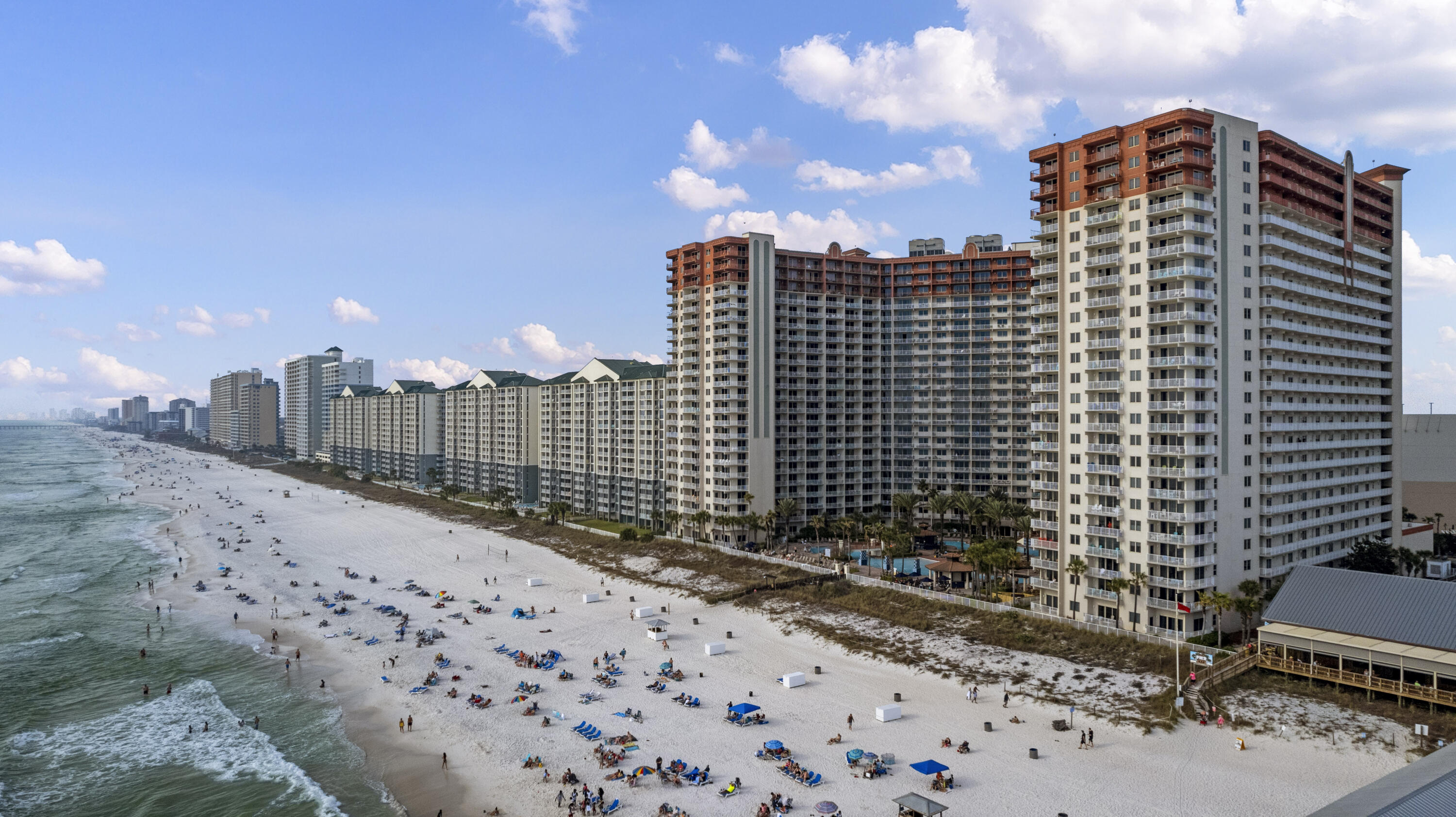 Beachfront condominium towers lining a white-sand beach beside the Gulf.