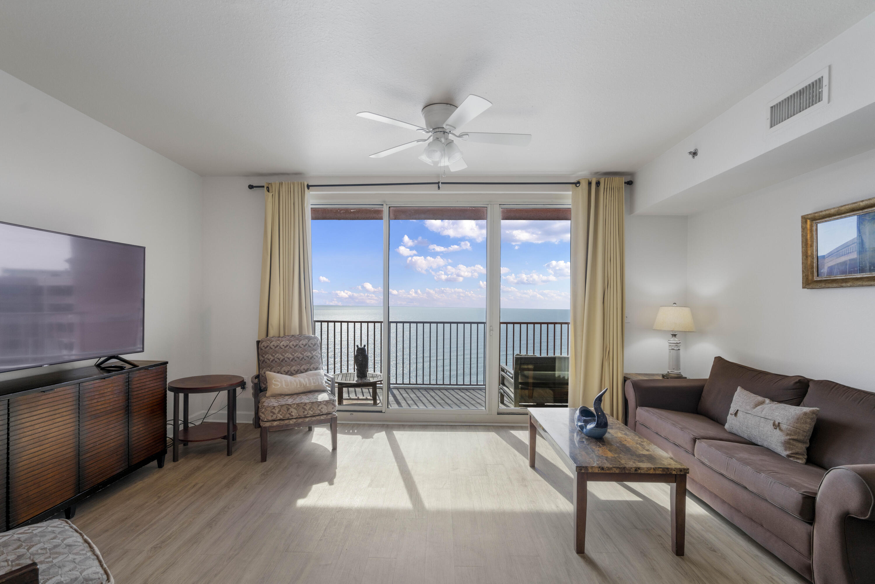 Furnished living room opens to a balcony with a wide ocean view.