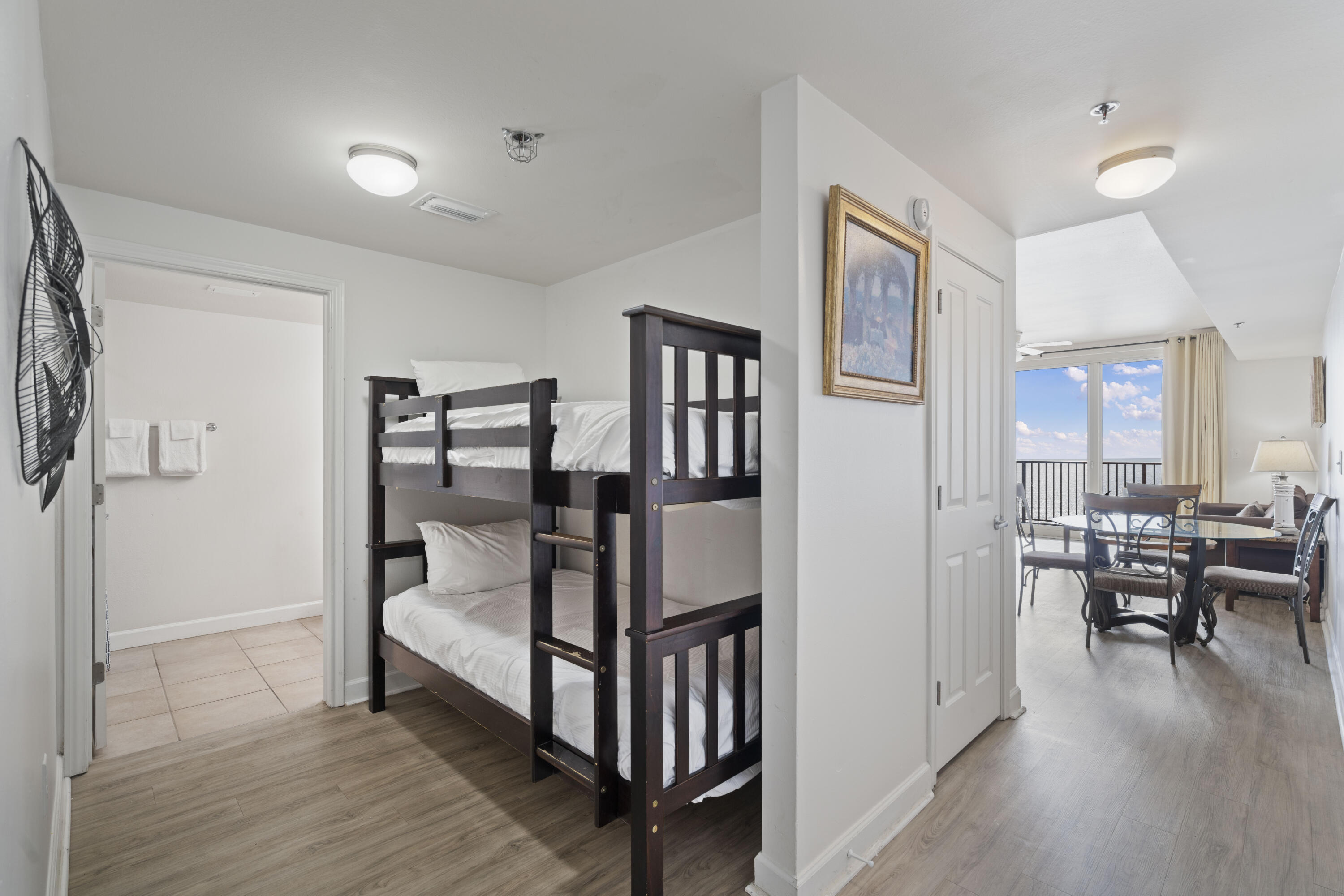 Condo bunk bedroom with dark wood bunk beds and a view through to the dining area and balcony.