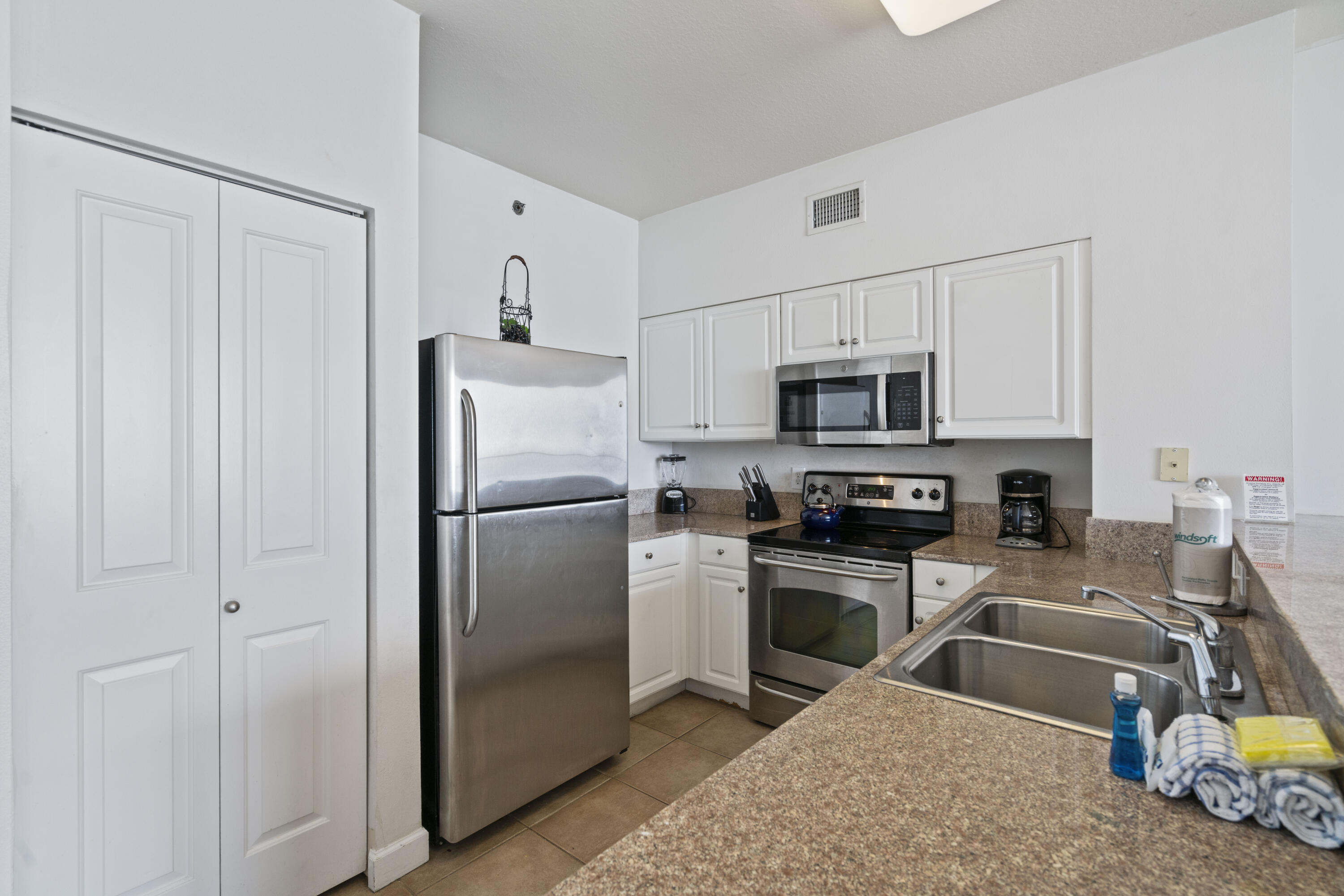 Condo kitchen with white cabinets, stainless steel appliances, and a double-basin sink.