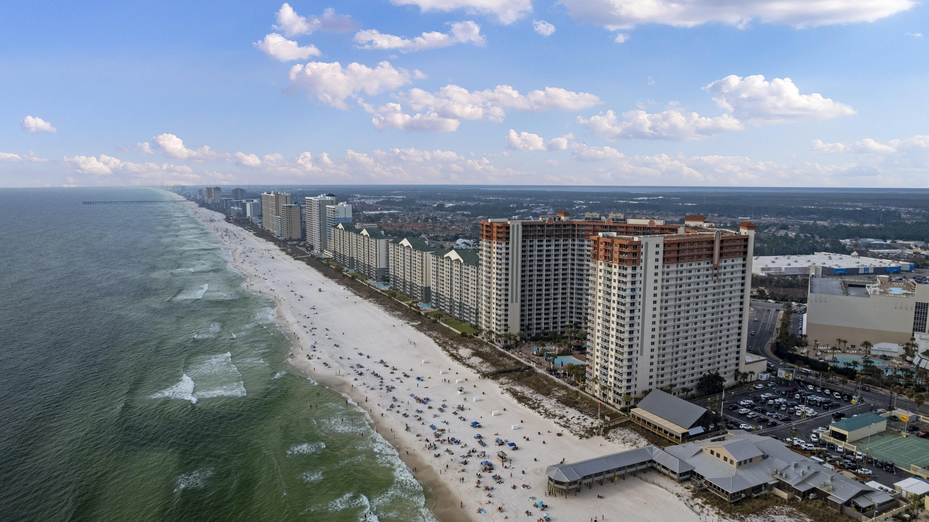 Aerial view of beachfront condominium towers and white-sand beach beside the Gulf.