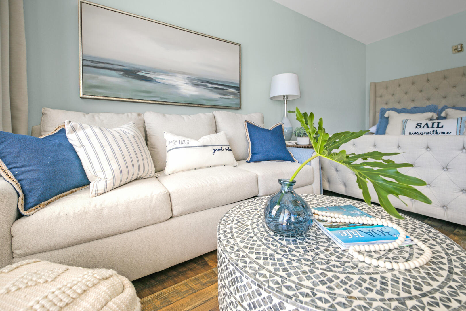 Living room with cream seating, blue coastal pillows, and a patterned round coffee table.