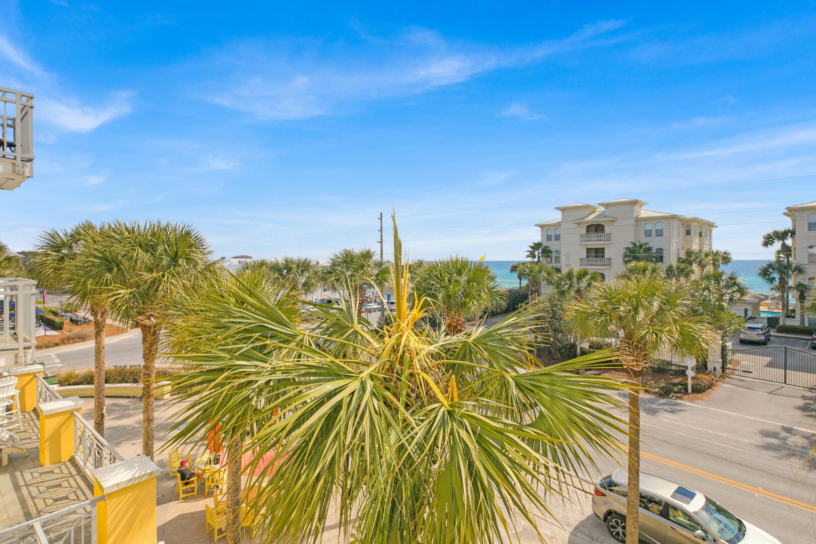 Coastal view with palm trees, neighboring buildings, and the turquoise Gulf beyond.