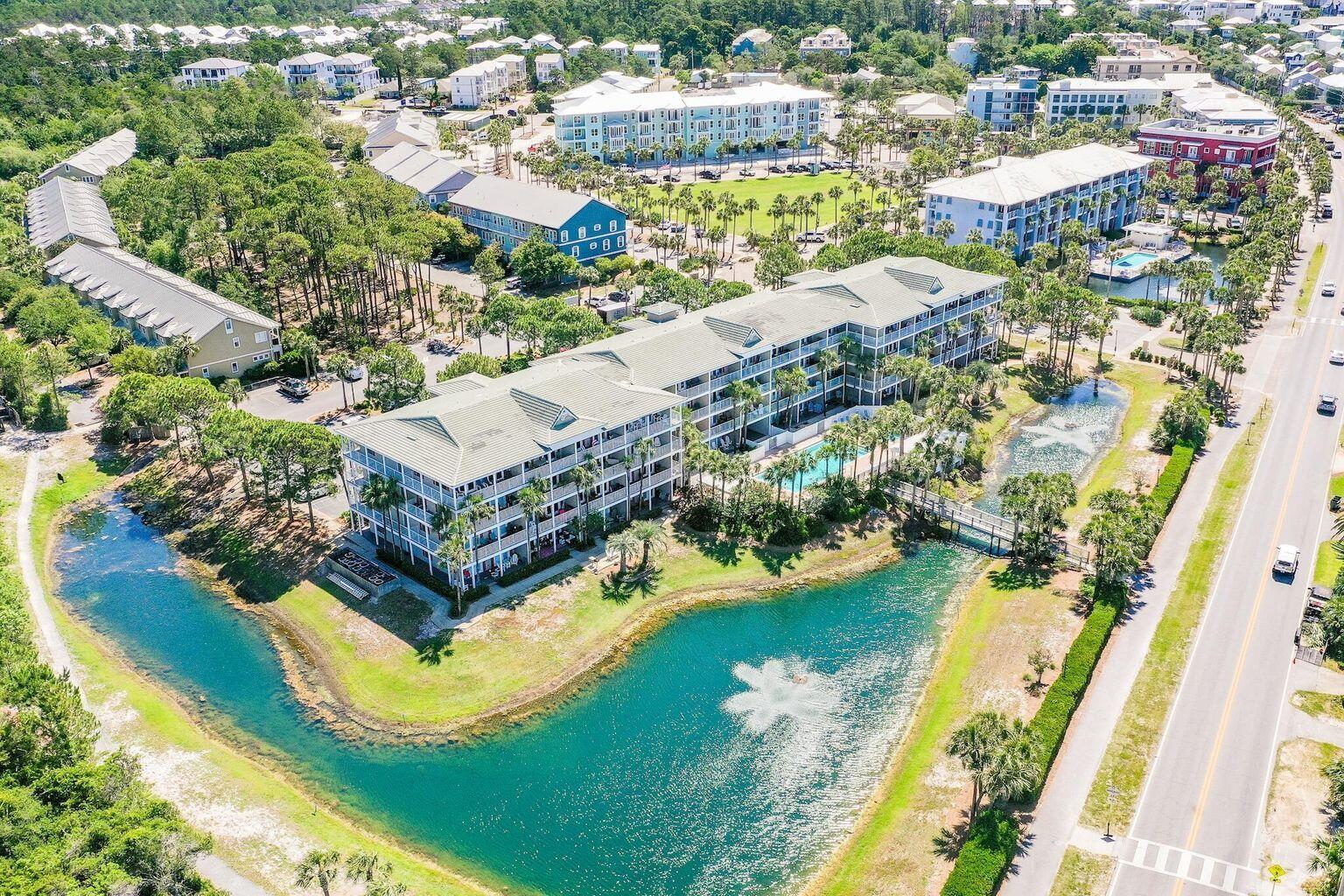 Aerial view of condominium buildings and pools beside a turquoise lagoon.