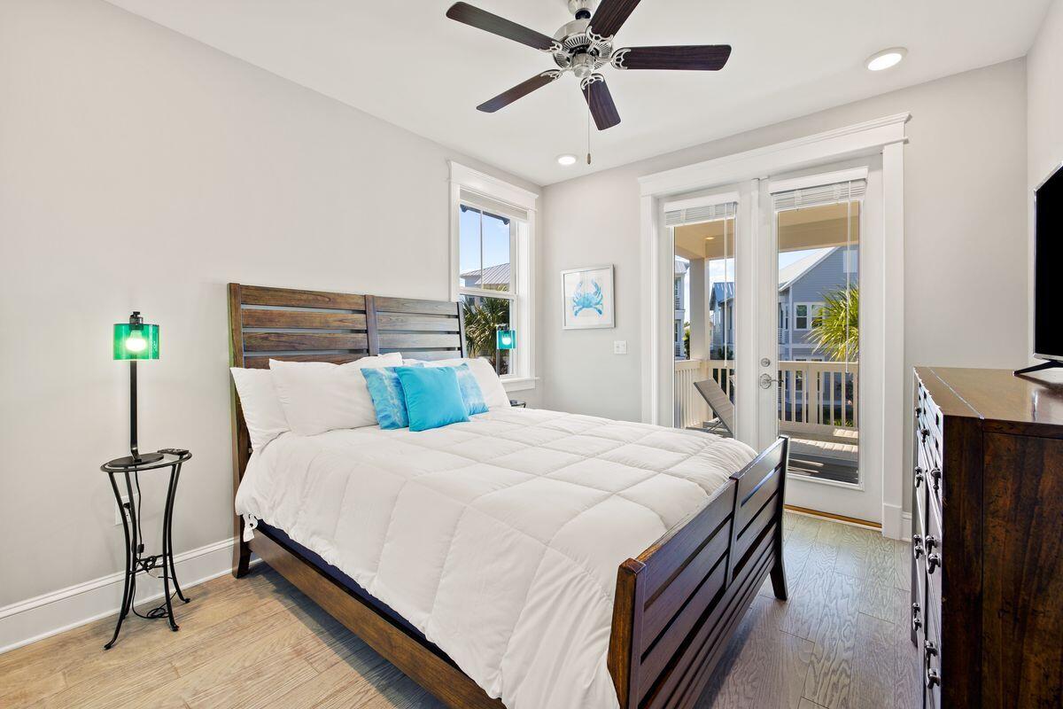 Bedroom with a dark wood bed, turquoise pillows, and glass doors opening to a balcony.