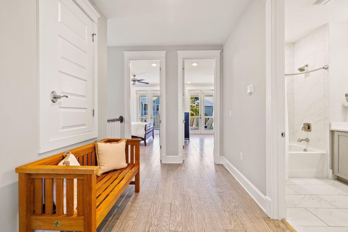Hallway with a wooden bench, bedroom doorways, and an adjoining marble-tiled bathroom.