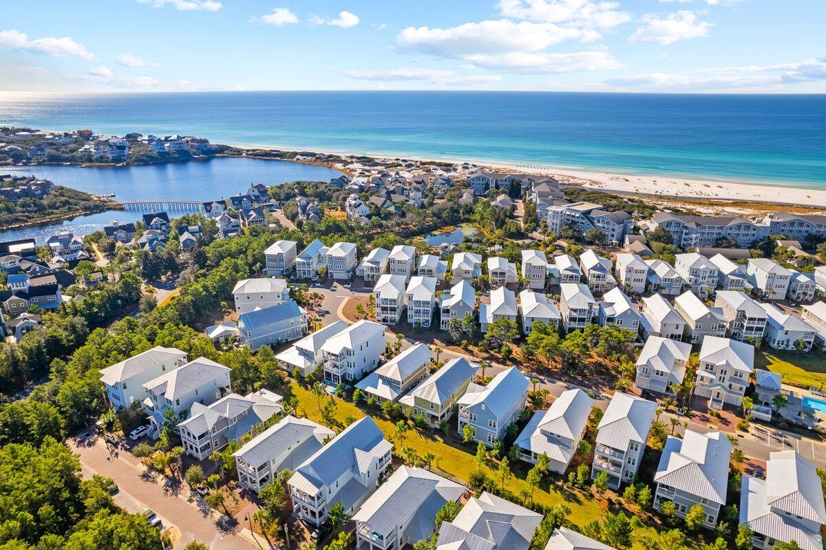 Aerial view of coastal homes beside a lagoon and sandy beach, with the ocean beyond.