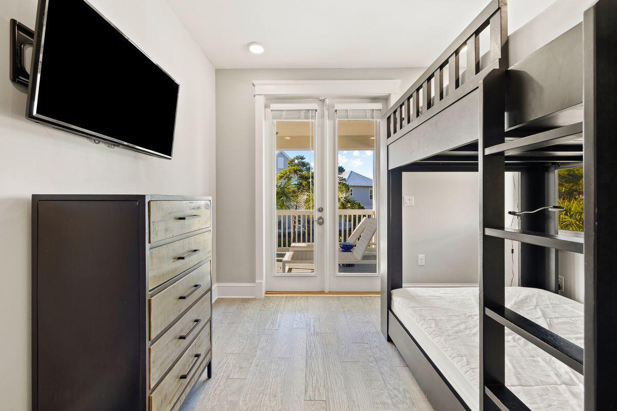 Bedroom with a black-framed bunk bed, dresser, and glass doors opening to a balcony.