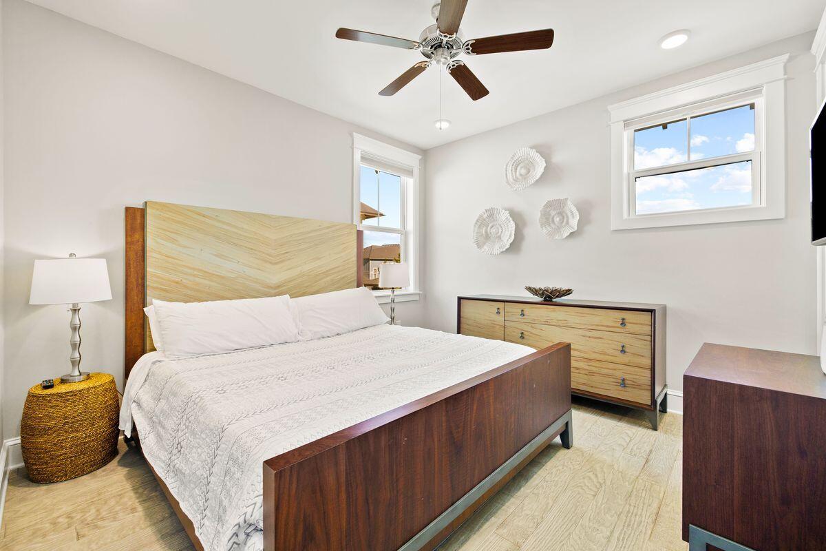 Bedroom with a wood-framed bed, white bedding, matching dresser, and shell wall decor.