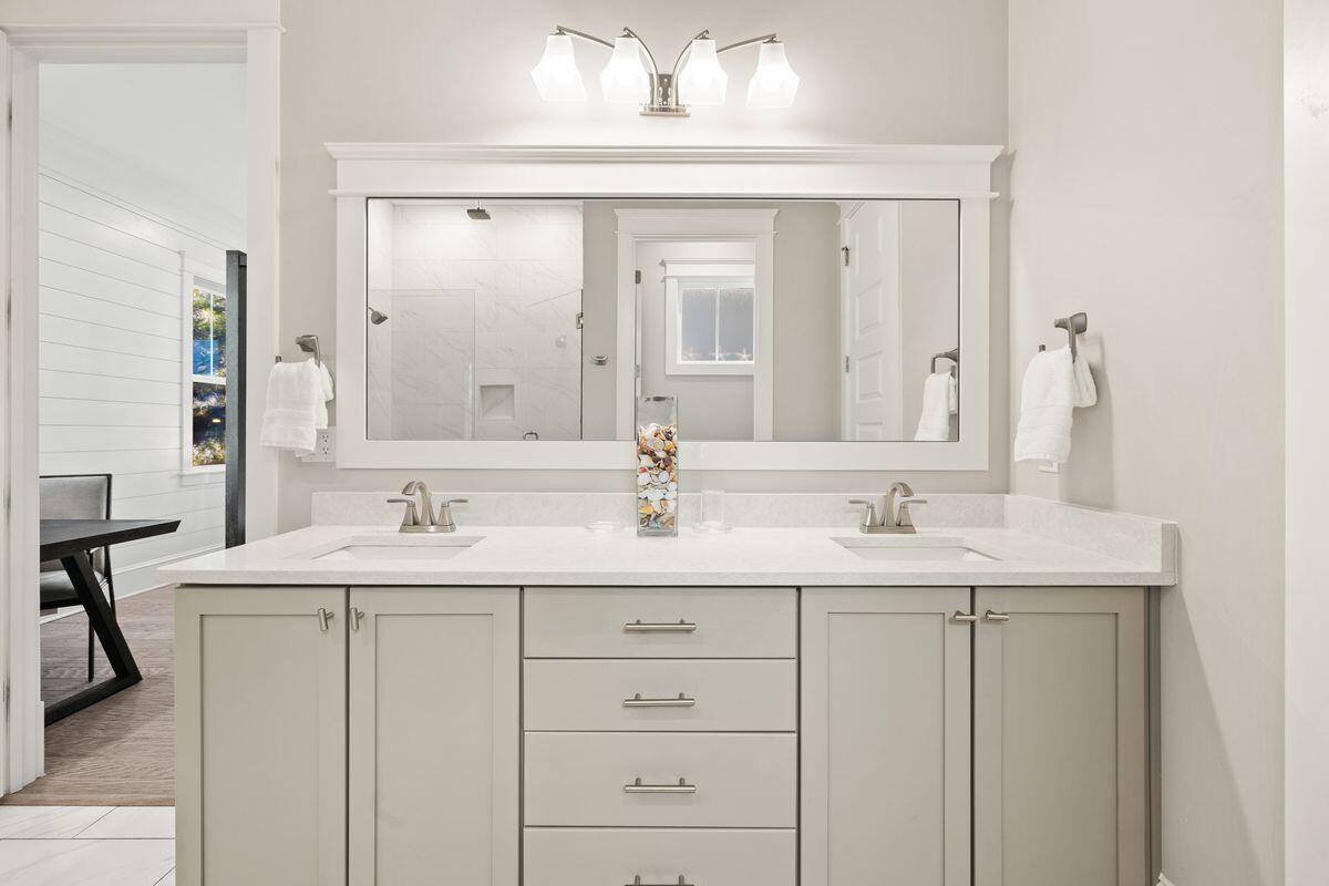 Bathroom with a double-sink vanity and large mirror reflecting a tiled shower.