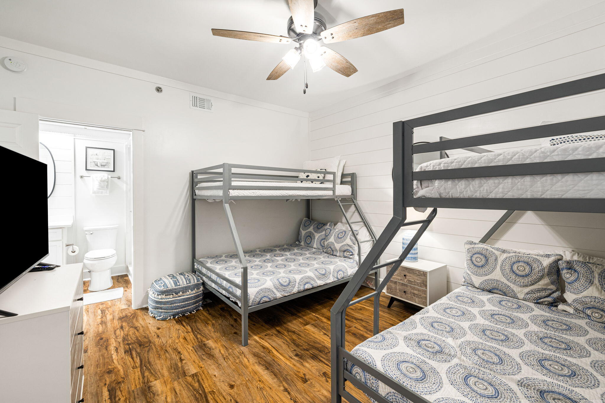 Bedroom with two gray bunk beds, blue patterned bedding, and an open doorway to a bathroom.