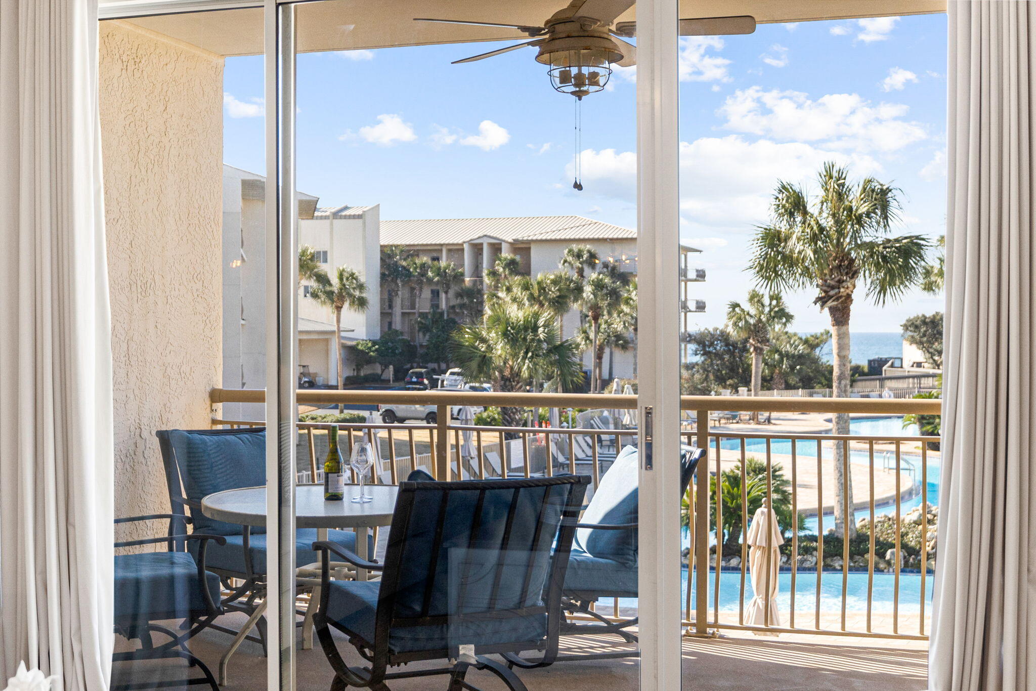 Furnished balcony overlooking a swimming pool and the ocean.