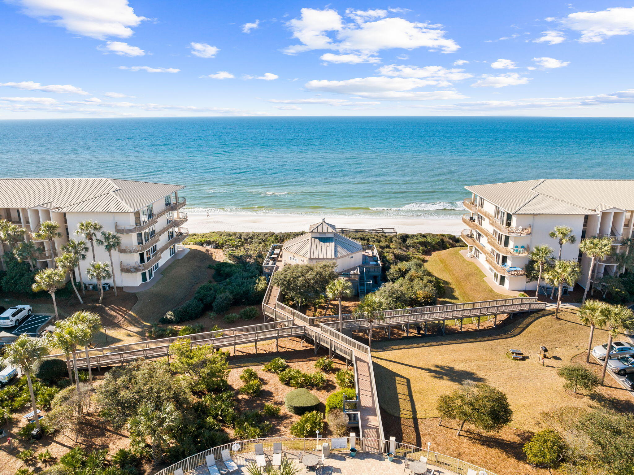 Beachfront condominium complex with boardwalks leading to a sandy shore and ocean.