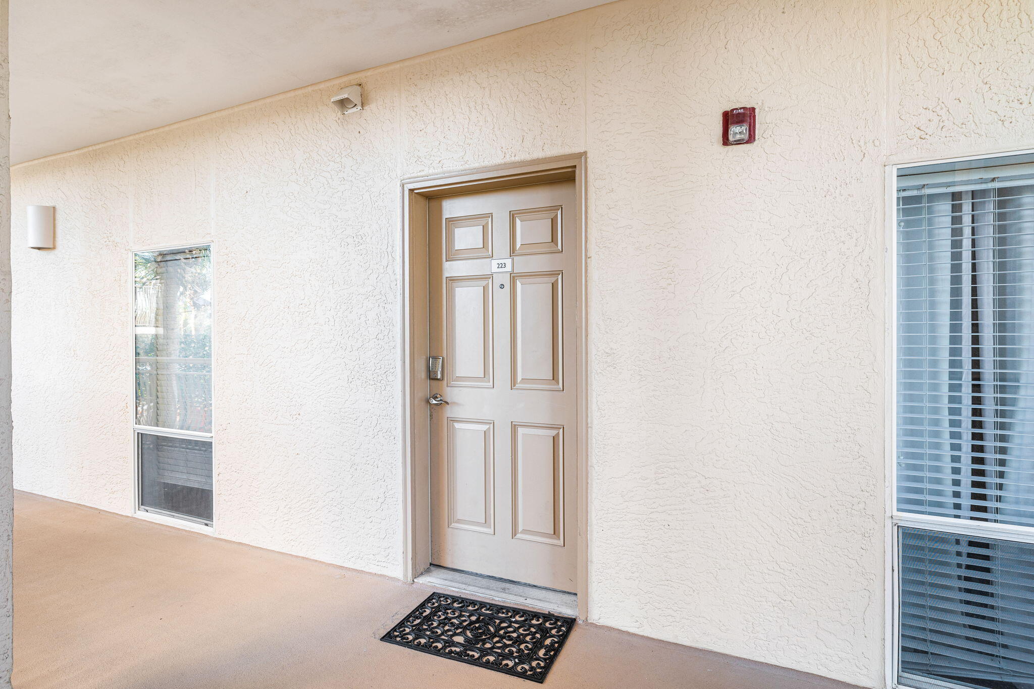 Condominium unit 223 entrance with a paneled door and decorative black doormat.
