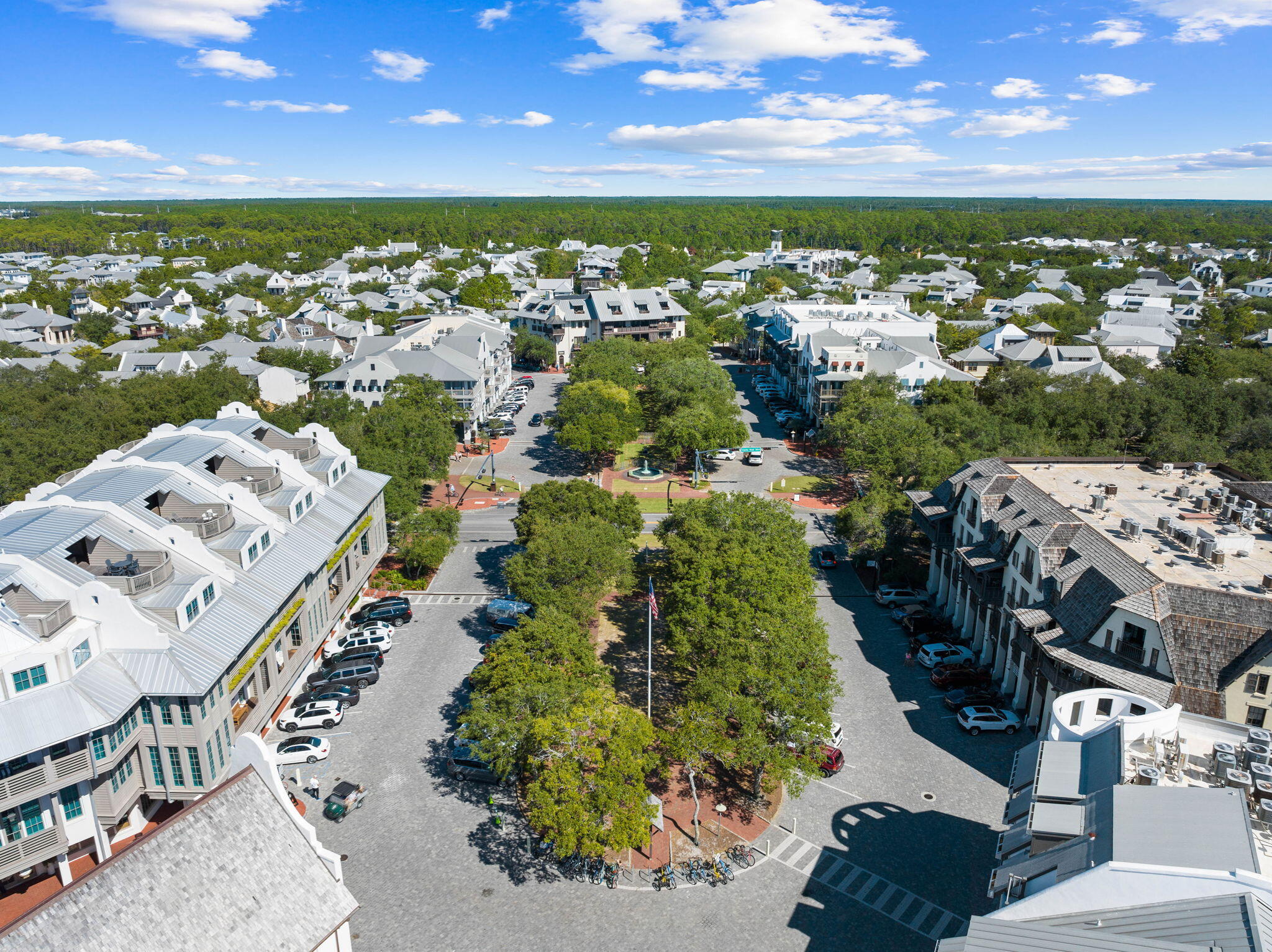 Aerial view of a leafy community, with low-rise buildings surrounding a landscaped central plaza.