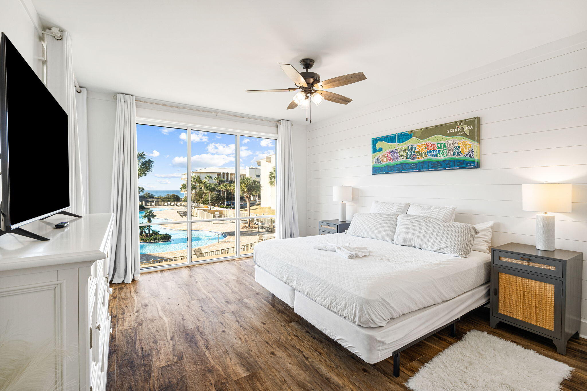 Bedroom with a king bed and sliding glass doors overlooking a pool and ocean.