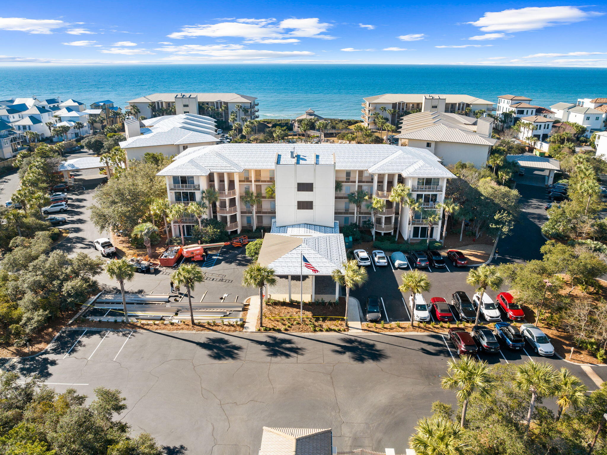 Aerial view of a beachfront condominium complex with the Gulf beyond and parking in front.