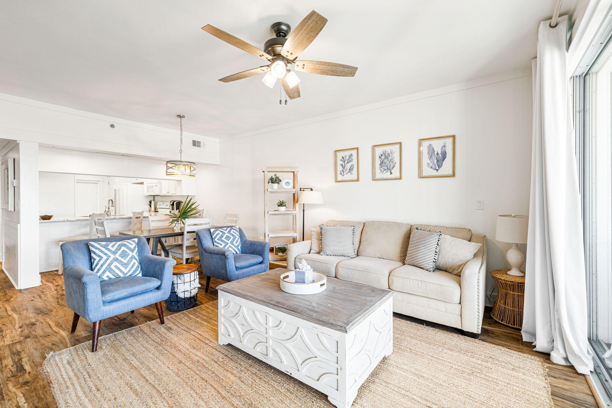 Open-plan living room with a beige sofa, blue armchairs, and sliding glass doors.