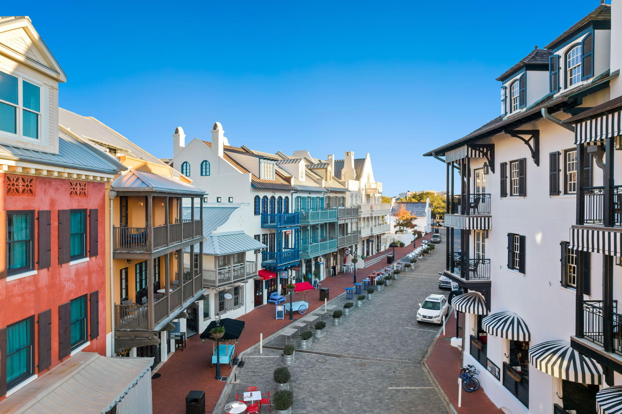 Pedestrian street lined with colorful buildings, balconies, and striped awnings.