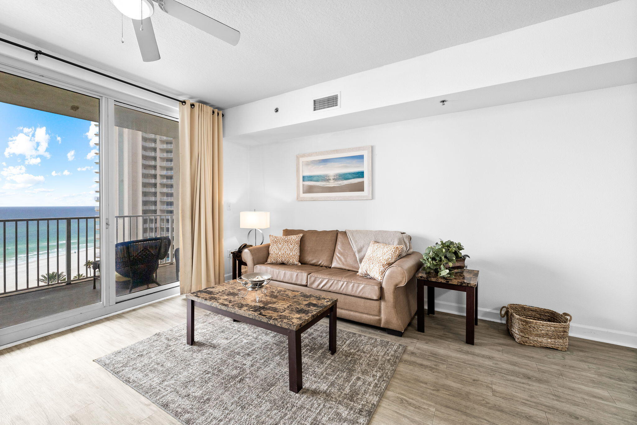 Condominium living room with a tan sofa and sliding doors overlooking the ocean.