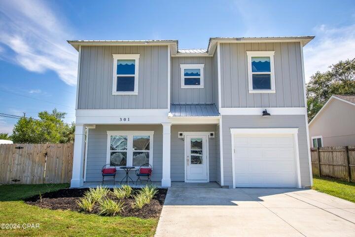 Two-story gray home with white trim, covered porch, and attached garage.