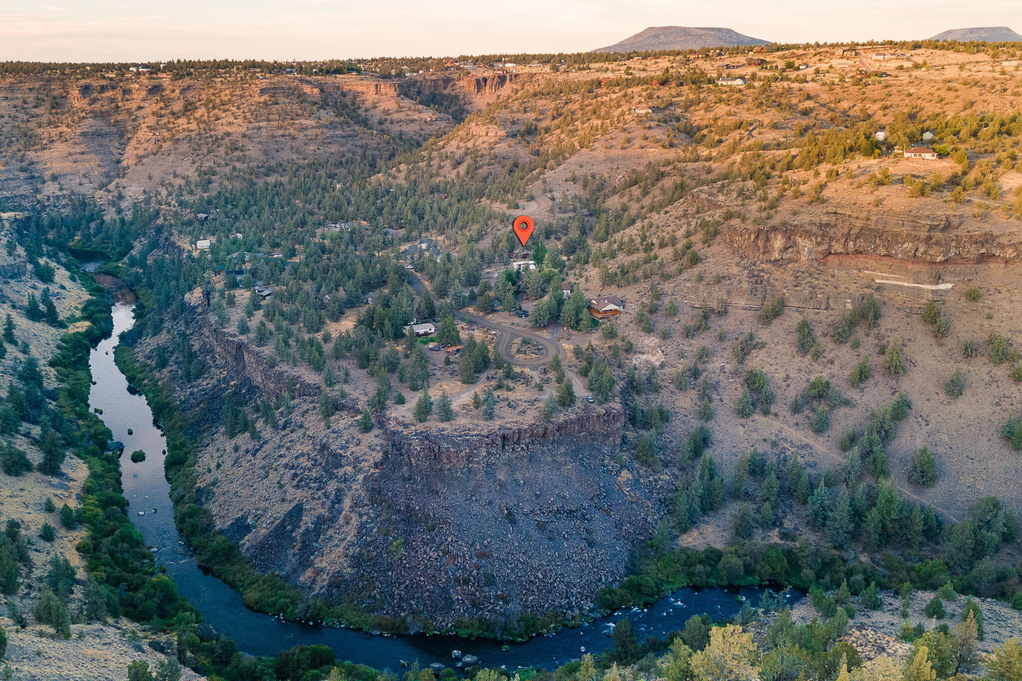 Aerial view of a canyon property marked by a red pin above a winding river.