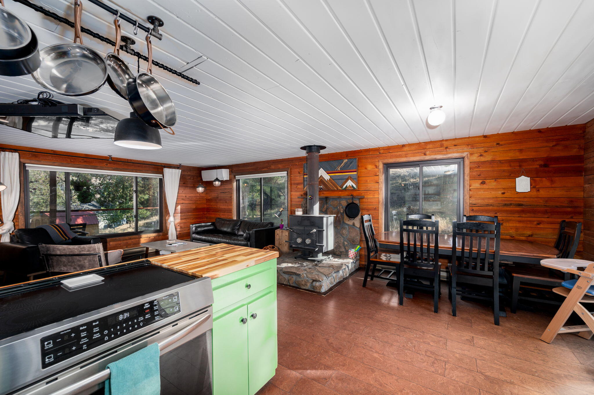 Open-plan kitchen and living area with a green island, wood-burning stove, and dining nook.