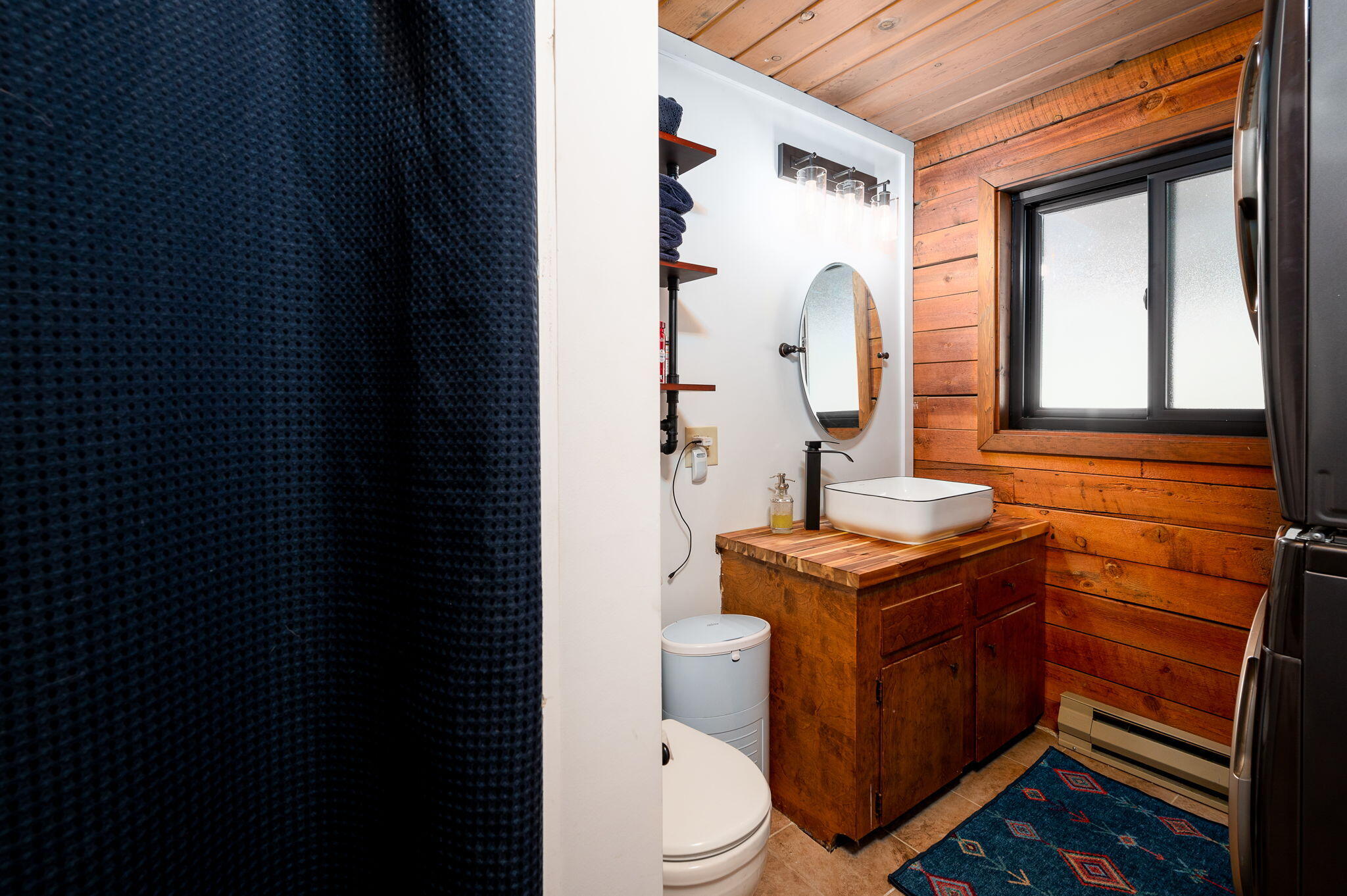 Bathroom with a wood-plank interior and a vessel sink on a wooden vanity.
