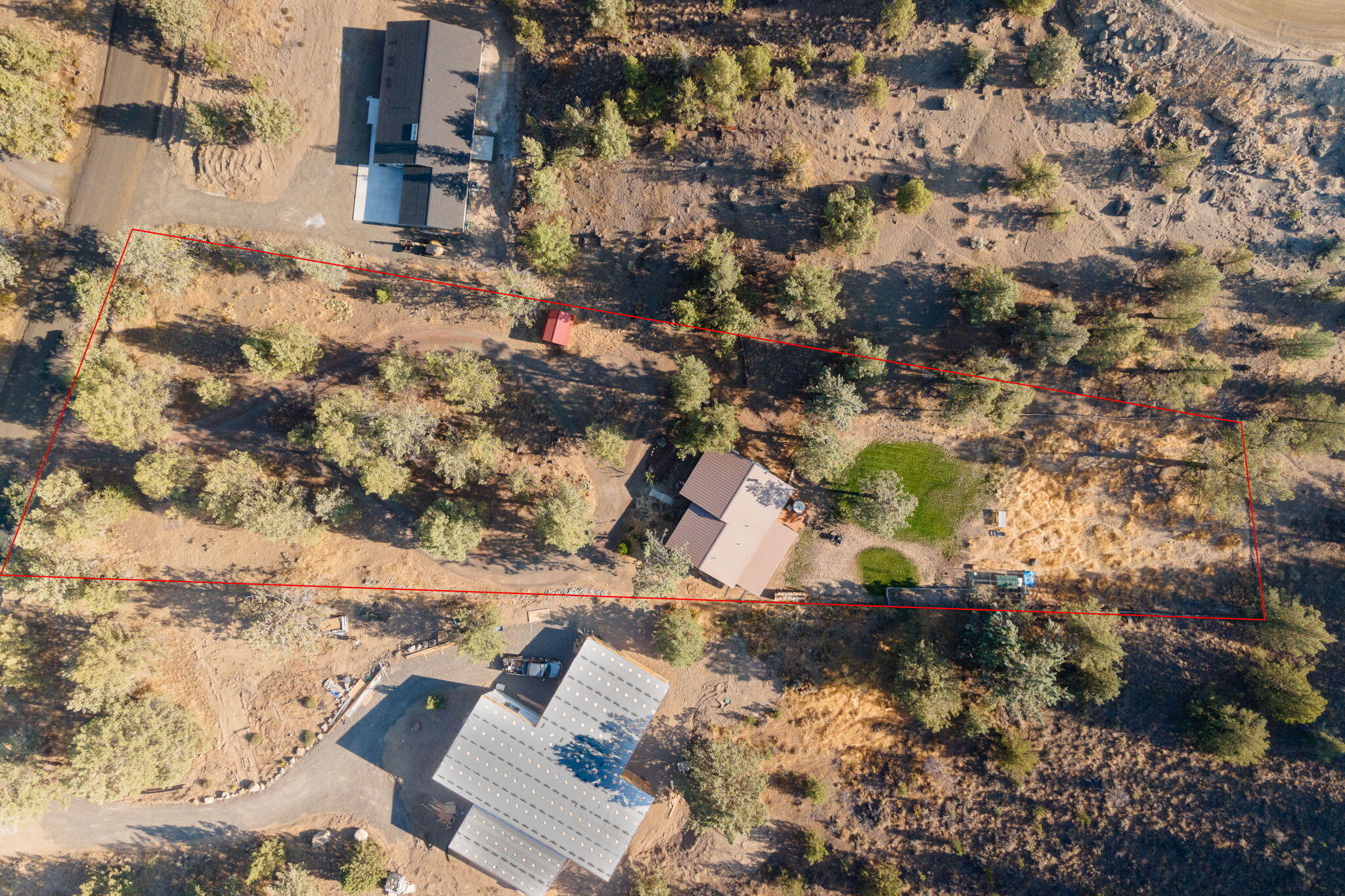 Aerial view of a wooded rural property outlined in red, with a house and driveway.