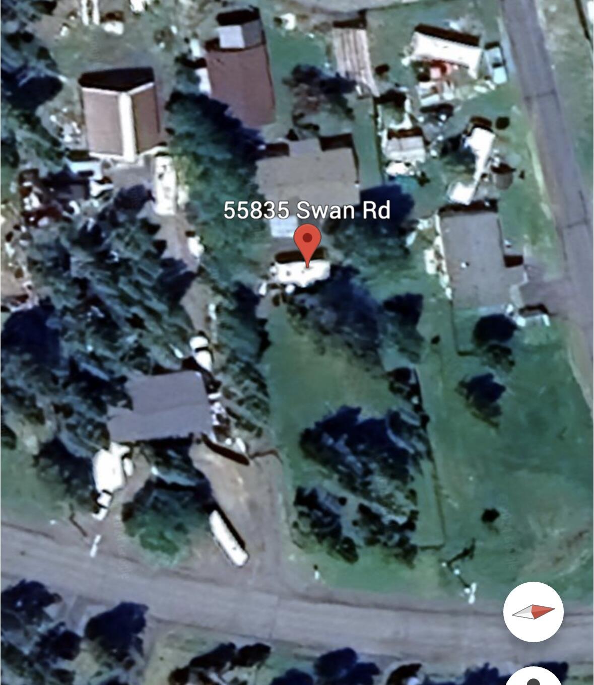 Aerial view of 55835 Swan Road, with the home, trees, neighboring properties, and nearby road.