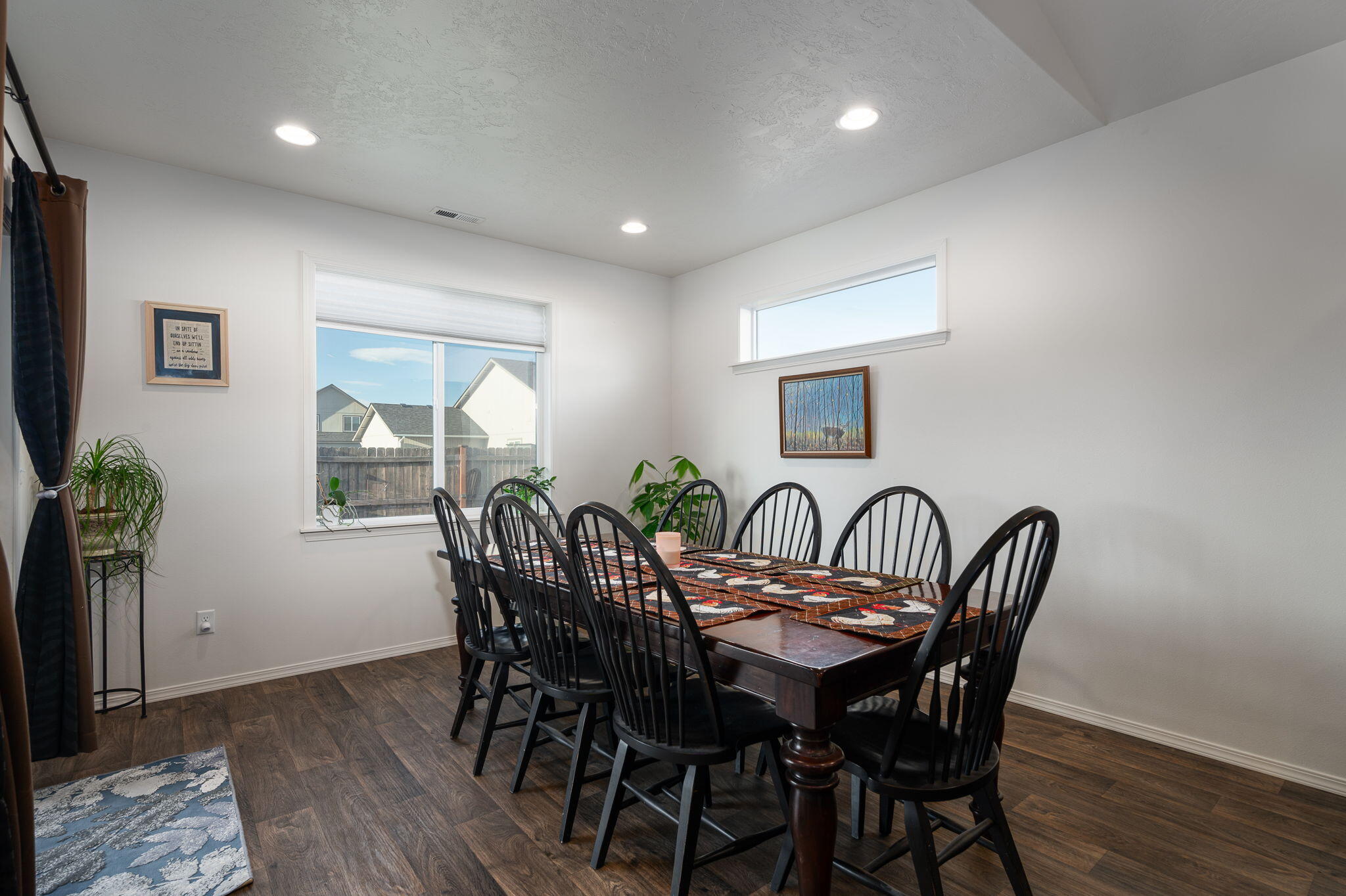 Dining room with a dark wood table, black chairs, and two large windows.