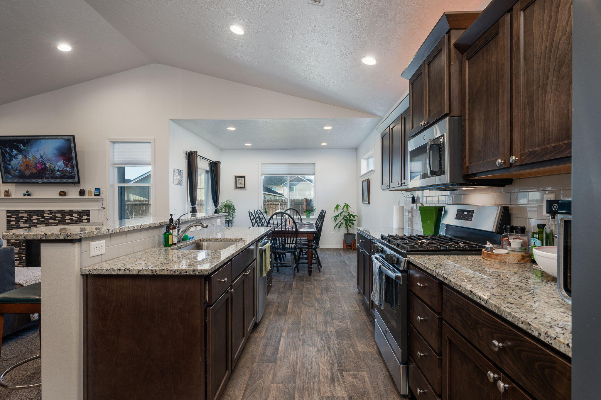 Kitchen with dark wood cabinets, granite island, stainless appliances, and an adjoining dining area.