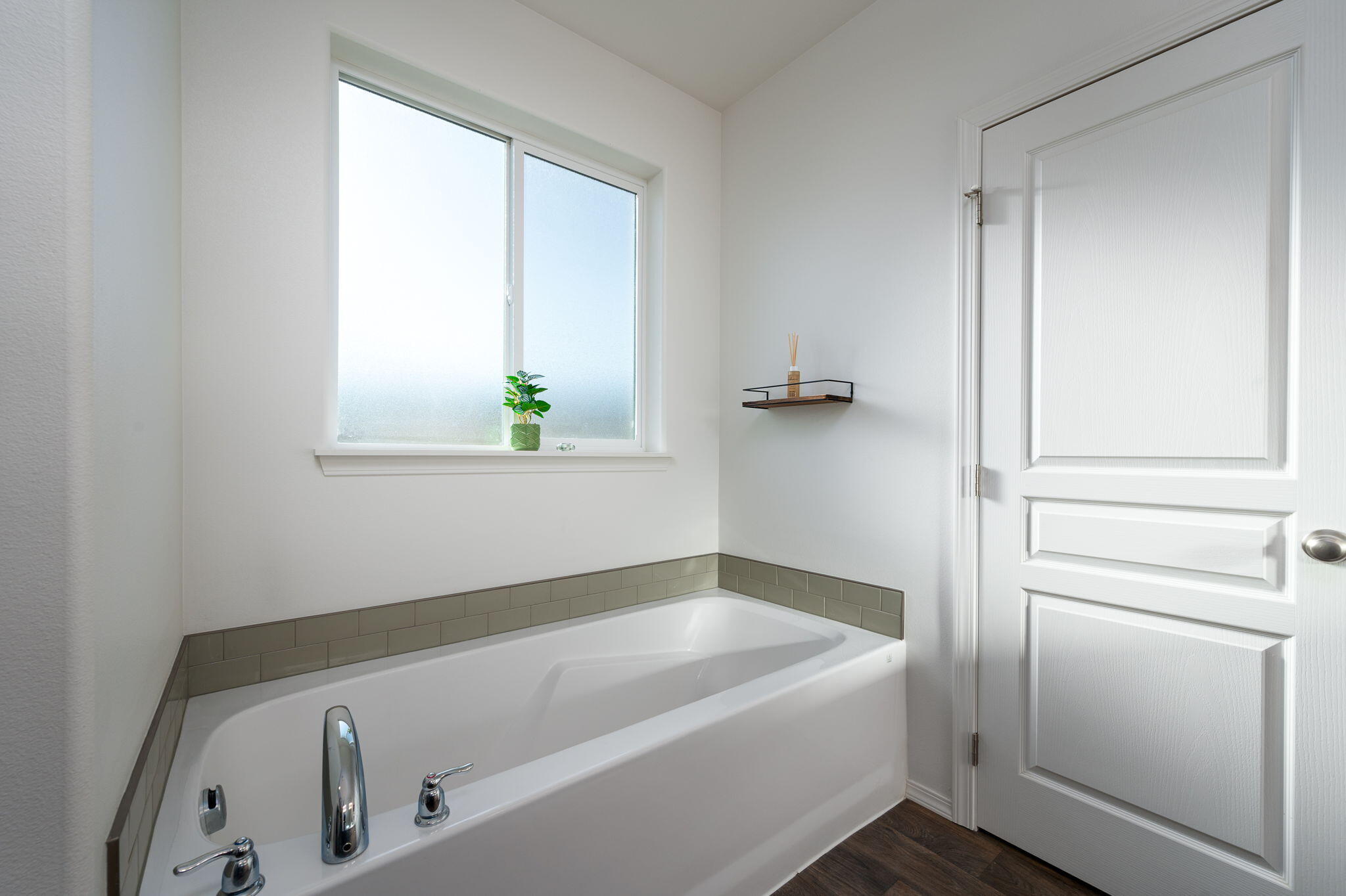 Bathroom with a built-in tub, green tile surround, and frosted window.