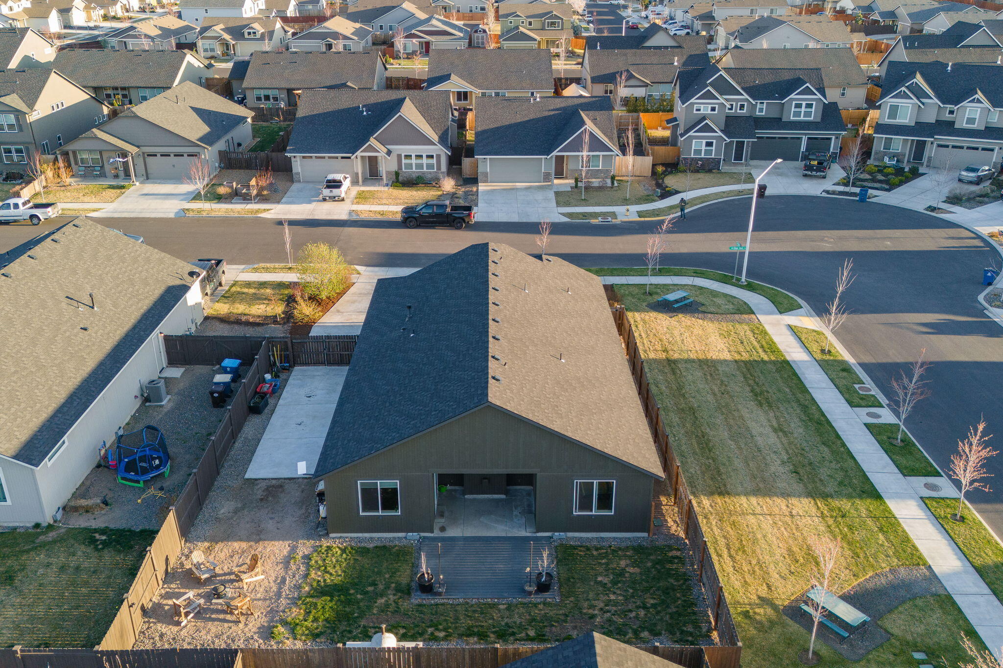 Aerial view of a single-story home with a fenced backyard, rear deck, and patio seating.