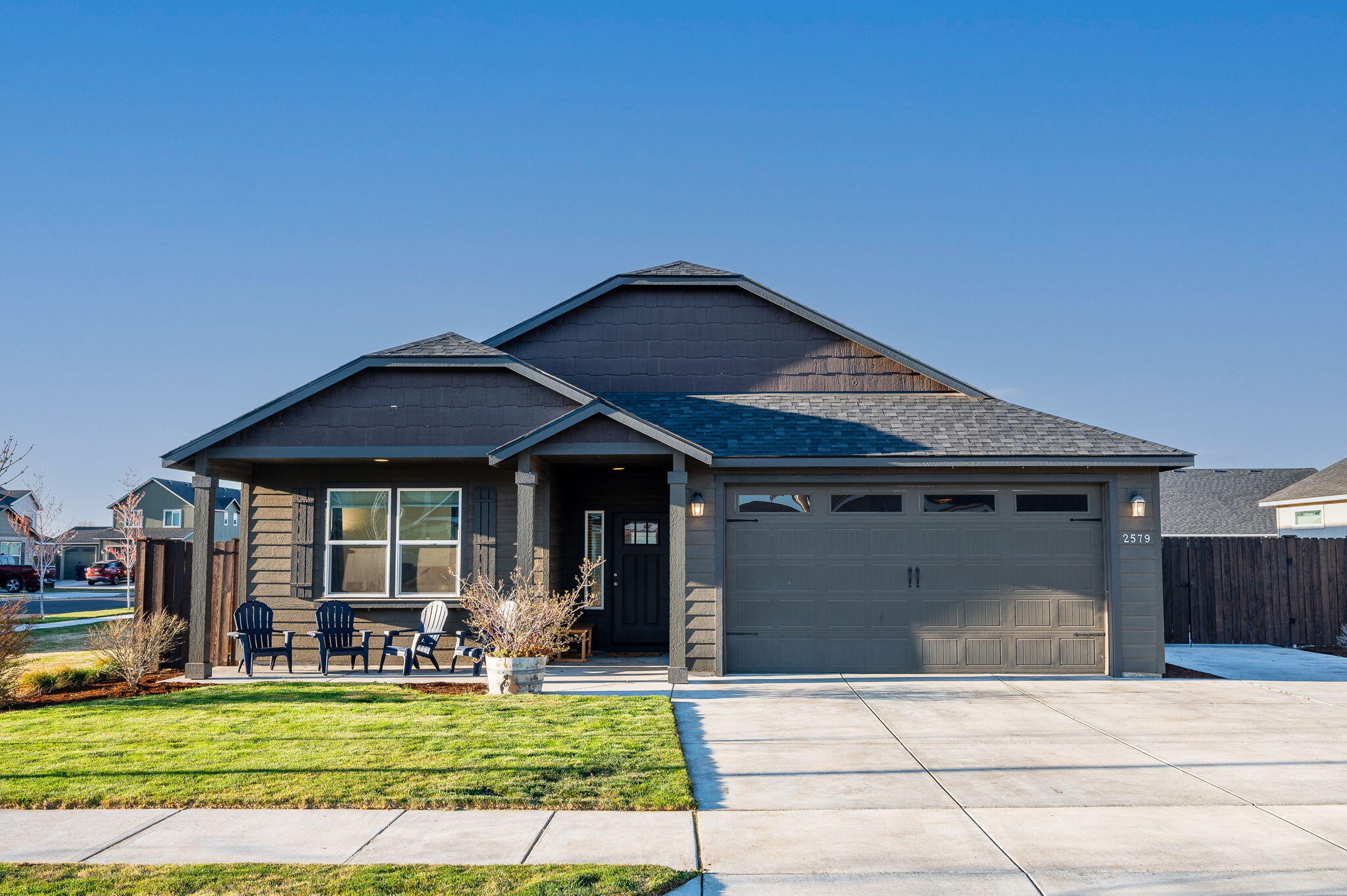 Gray single-story home with a covered porch, two-car garage, and front lawn.