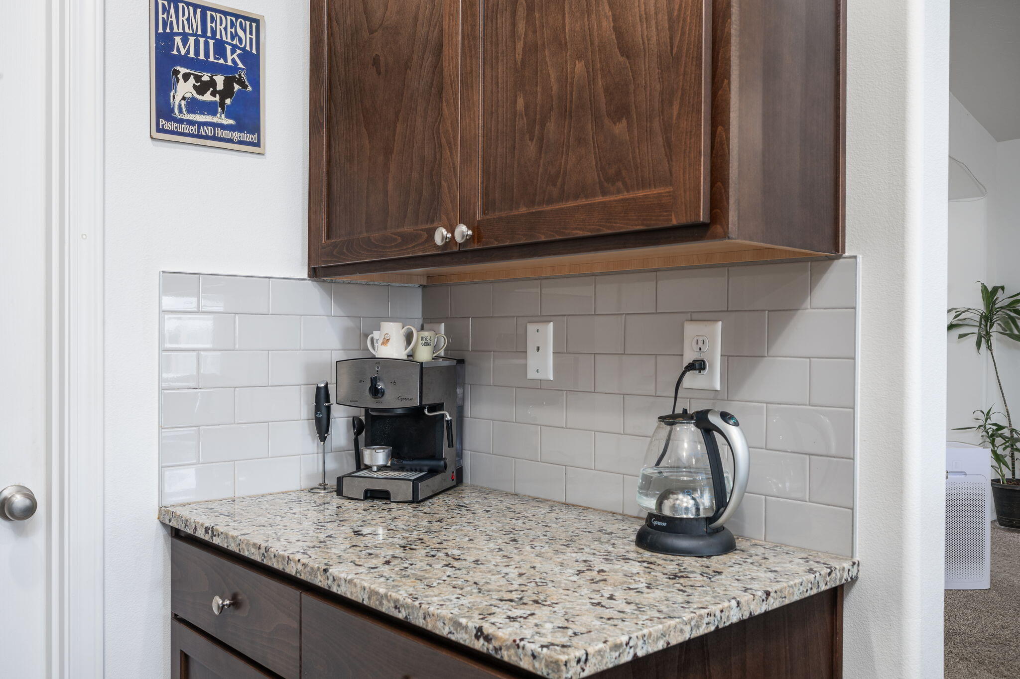 Kitchen coffee station with dark wood cabinets, a granite counter, an espresso machine, and an electric kettle.