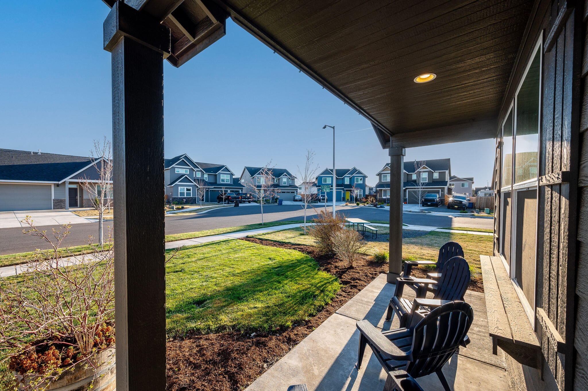 Covered patio with Adirondack chairs overlooking a lawn and neighborhood homes.