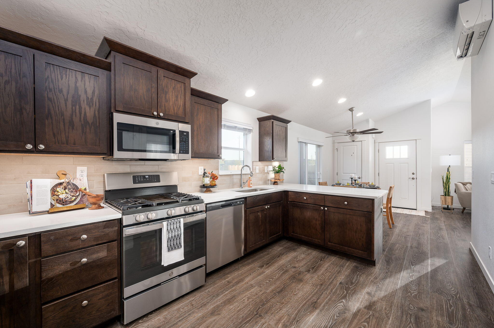 Kitchen with dark wood cabinets, stainless steel appliances, and a large white-counter island.