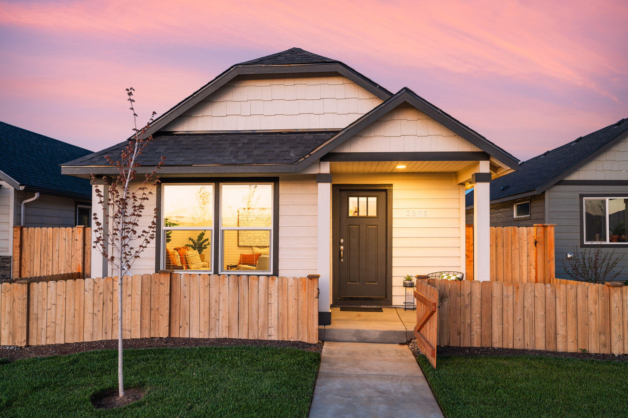 House front with a covered entry, wooden fence, and walkway at golden hour.