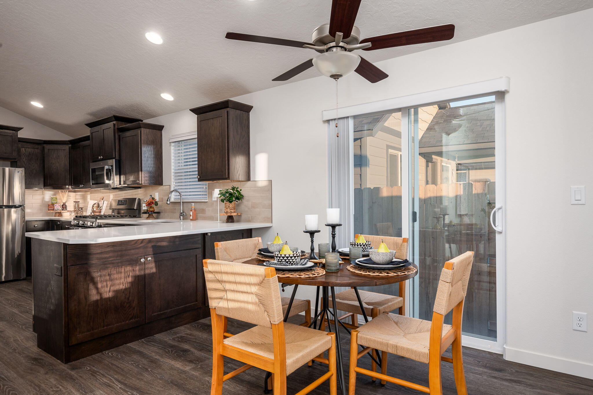 Kitchen and dining area with dark wood cabinets, a set table, and a sliding glass door.