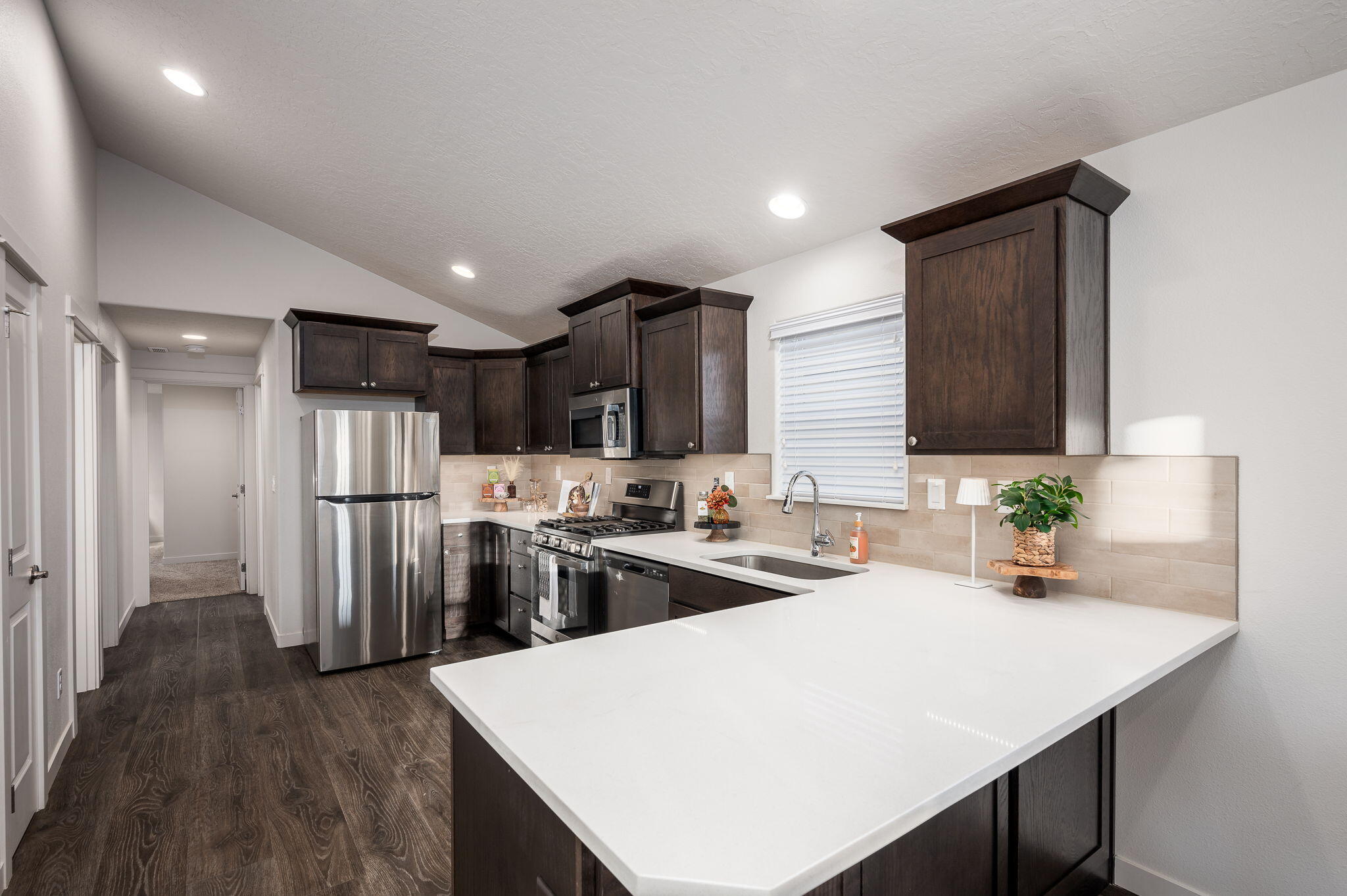 Kitchen with dark wood cabinets, stainless steel appliances, and a large white peninsula countertop.