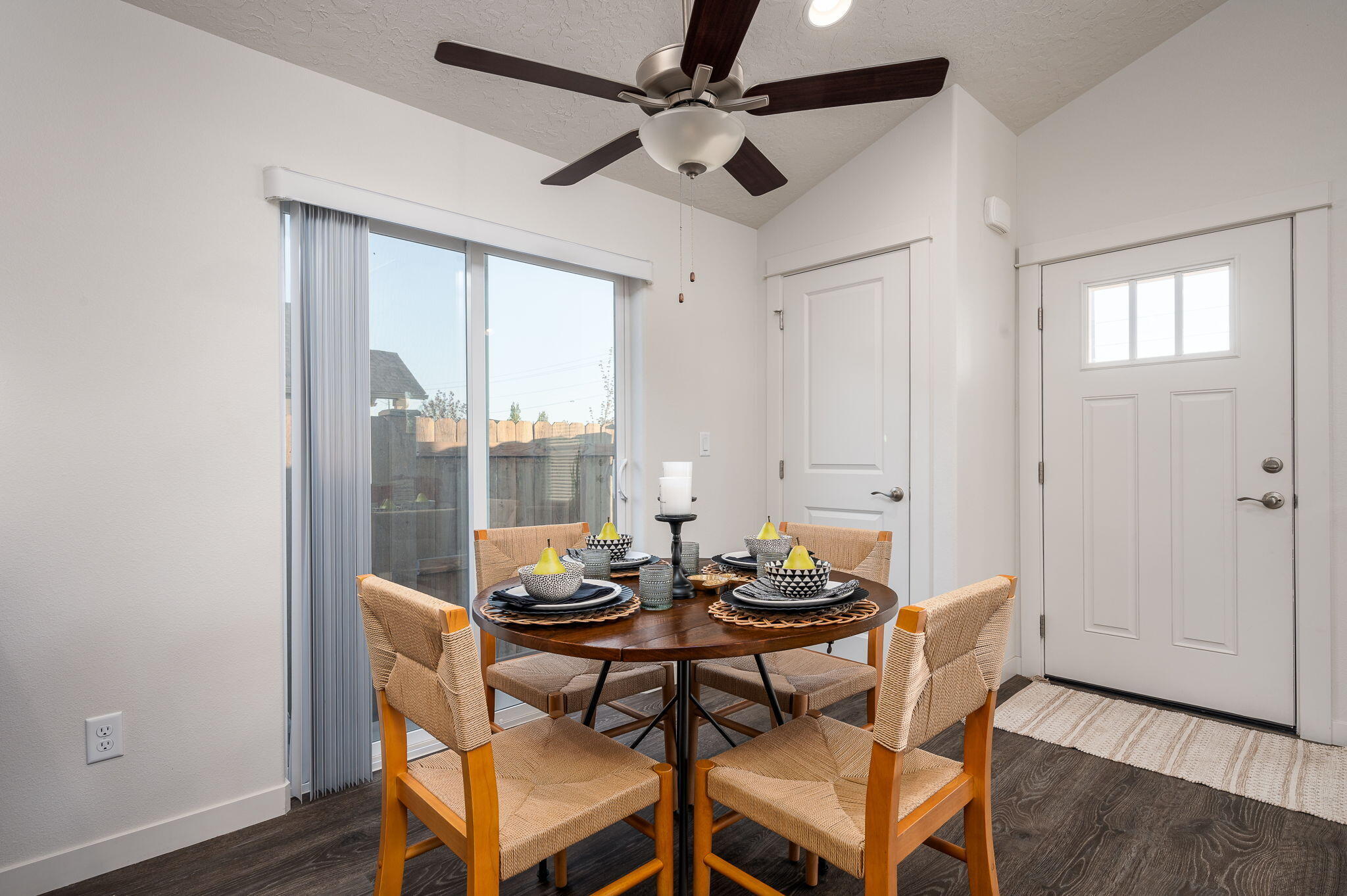 Dining room with a round table set for four beside sliding glass doors.