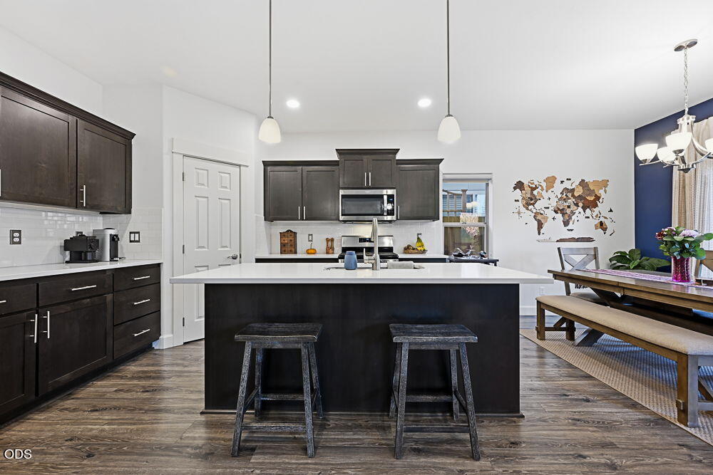 Open-plan kitchen with dark cabinets, a large white-topped island, and a dining table with bench seating.