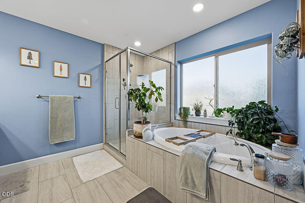 Bathroom with a glass shower and built-in soaking tub beneath a large window.