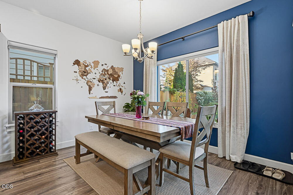 Dining room with a wooden table, chandelier, blue accent wall, and wine rack by the window.
