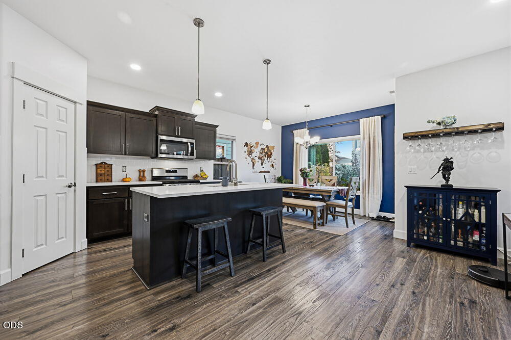 Open-plan kitchen with dark cabinets, a large island, and a dining table beside a glass patio door.