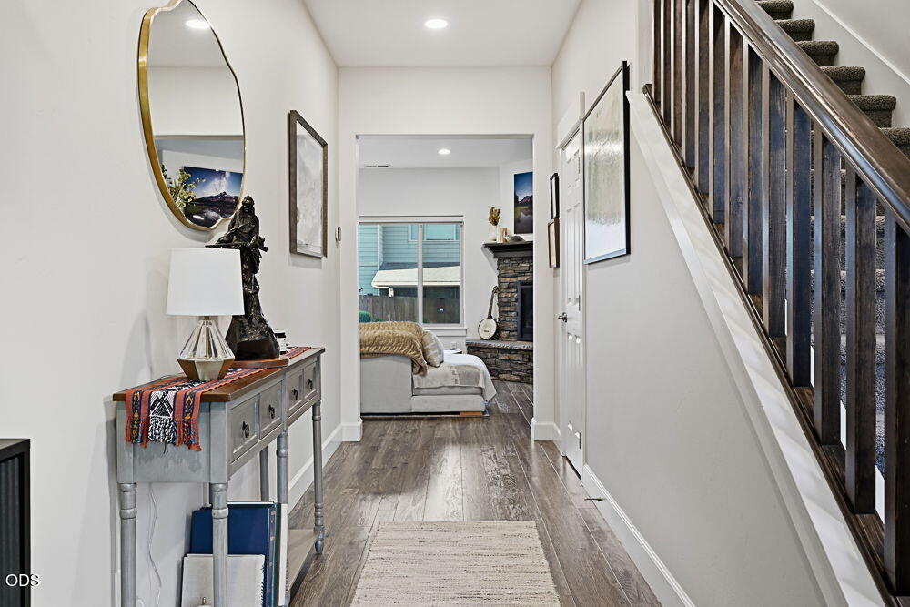 Entry hallway with dark-railed staircase, console table, and sitting area with stone fireplace.