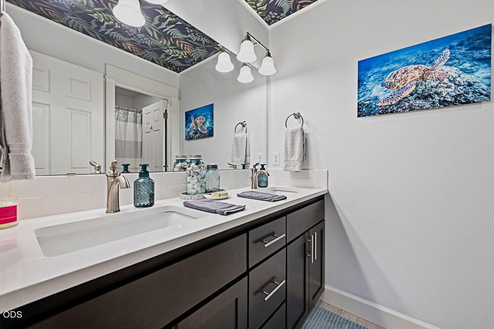 Bathroom vanity with dark cabinets, a white countertop, and sea turtle artwork.