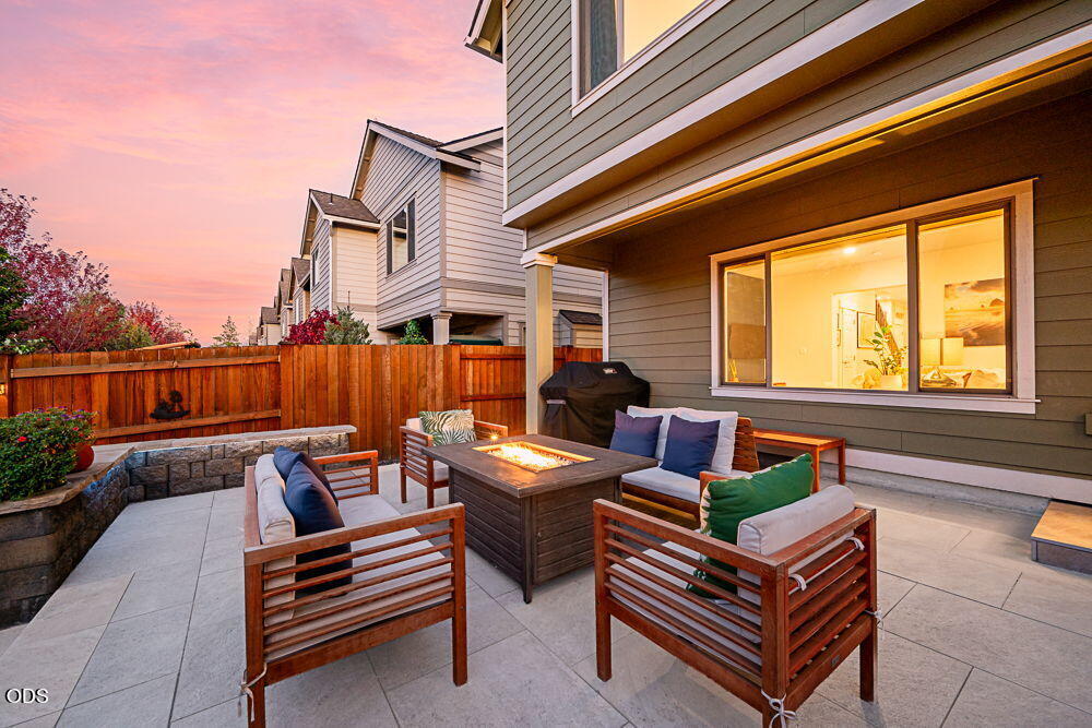 Townhouse patio with cushioned seating around a glowing fire table at dusk.
