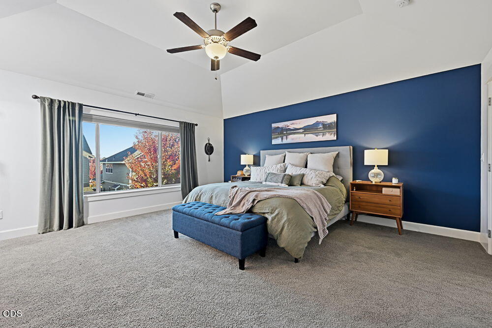 Staged bedroom with a king bed, deep blue accent wall, upholstered bench, and large window.
